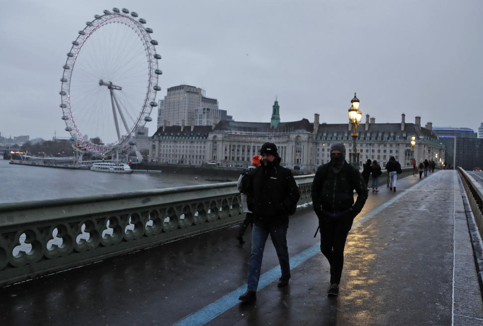 FILE - Commuters walk through light snowfall on Westminster Bridge as temperatures dropped below freezing in London, Tuesday, Feb. 9, 2021. On Friday, Dec. 2, 2022 The Associated Press reported on stories circulating online incorrectly claiming new figures from the United Kingdom’s Office for National Statistics shows that three of the country’s largest cities, London, Manchester and Birmingham, are now all “minority white.” (AP Photo/Frank Augstein, File)