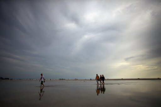 Personas paseando por una playa de Treasure Island, en el Estado de Florida (EEUU), el jueves 23 de agosto. La arena de la playa está inundada de agua por las fuertes lluvias de los últimos días mientras la zona se prepara para la posible llegada de la tormenta tropical Isaac. (AFP/Getty Images | Joe Raedle)