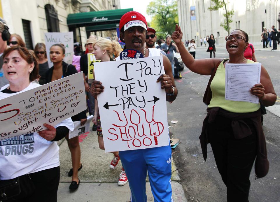 Members of the Occupy Wall Street movement hold signs as they protest on 5th Avenue while marching through the upper east side of New York