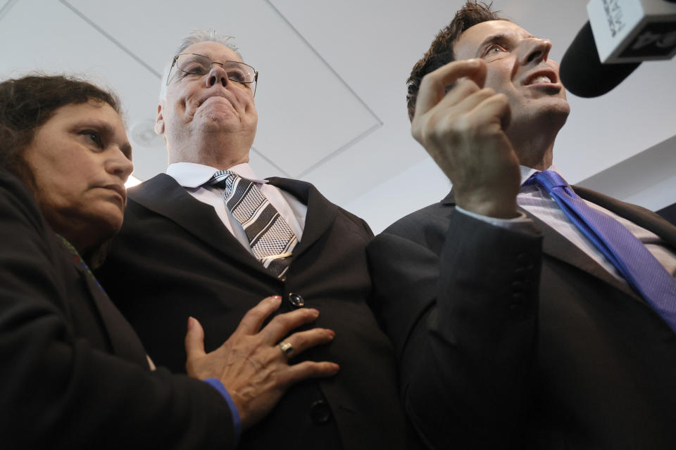 Former Marjory Stoneman Douglas High School School Resource Officer Scot Peterson holds his wife, Lydia Rodriguez, as his defense attorney, Mark Eiglarsh, right, gives a media interview after Peterson was found not guilty on all charges at the Broward County Courthouse in Fort Lauderdale, Fla., on Thursday, June 29, 2023. Peterson was acquitted of child neglect and other charges for failing to act during the Parkland school massacre, where 14 students and three staff members were murdered. (Amy Beth Bennett/South Florida Sun-Sentinel via AP, Pool)