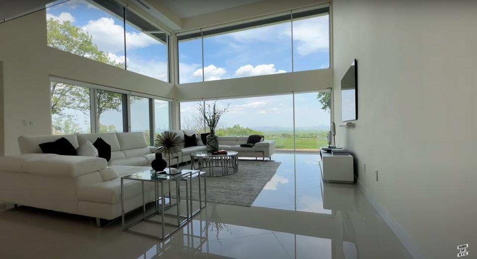 A white, modern living room with large windows.