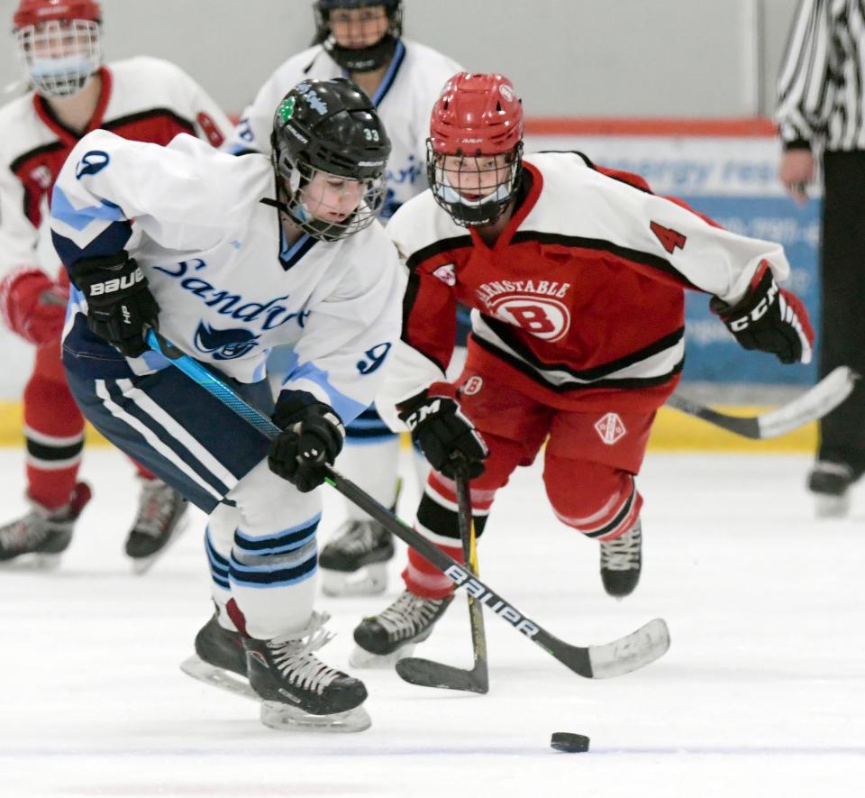 BOURNE 12/29/21  Meghan Barrett of Sandwich pushes the puck ahead of Claire Hazard of Barnstable.