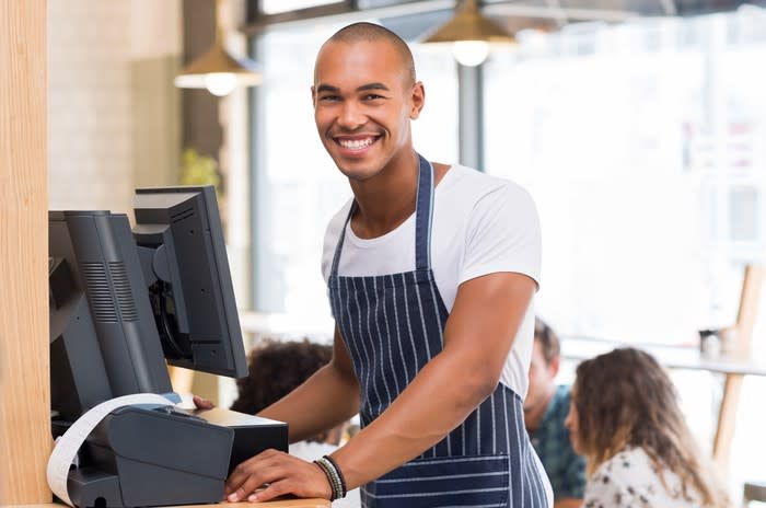 A young man working as a server in a restaurant.