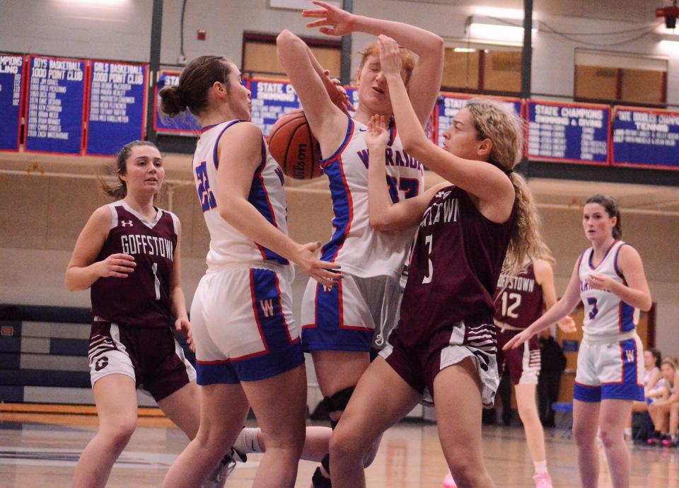 Winnacunnet's Casey Coleman, center, gets hit in the nose by Goffstown's Ava Ruggiero as Winnacunnet's Abby Wilber (22)  and Rio Franzoso (3) look on during Tuesday's Division I girls basketball game in Hampton.