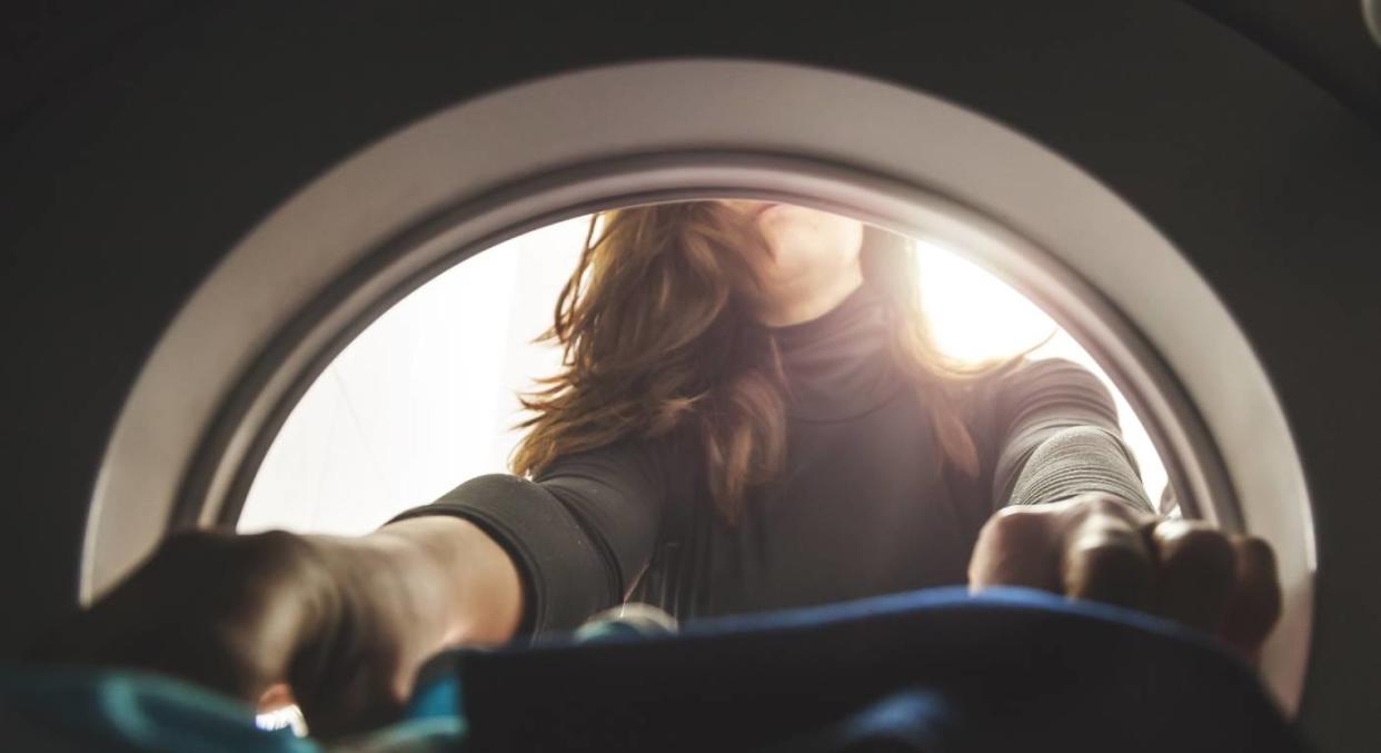 Woman puts laundry into the washing machine [Photo: Getty]