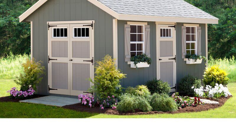 tiny cottage with flower beds surrounding and large double doors