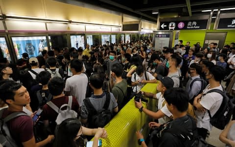 Passengers queue up at a subway platform in Hong Kong, where protesters have disrupted subway services during the morning commute by blocking the doors on trains, preventing them from leaving the stations.  - Credit: Vincent Yu/AP