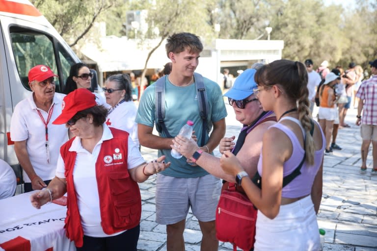 La Cruz Roja Helena distribuye botellas de agua entre los turistas el 17 de julio de 2024 en la Acrópolis, en Atenas (Aris Oikonomou)