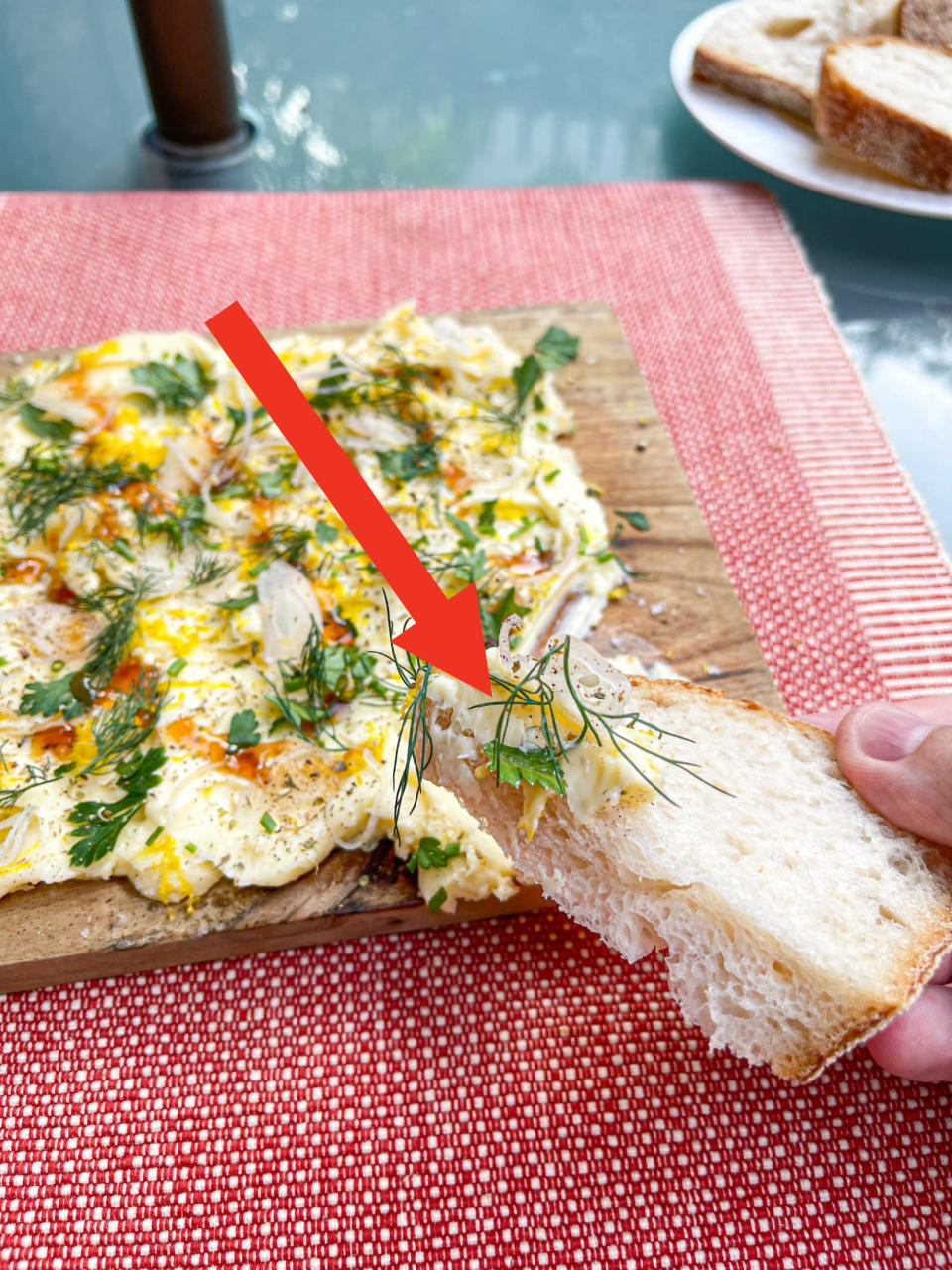 arrow pointing to various herbs on a piece of bread with butter