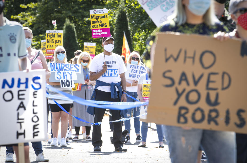 National Health Service (NHS) workers pose with placards, during a socially distanced demonstration as part of a national protest over pay, in Glasgow, Scotland, Saturday Aug. 8, 2020. Nationwide protests on Saturday are calling for government to address what they claim is many years of reduced wages, and are calling for a voice in plans for public sector pay increases. (Jane Barlow/PA via AP)