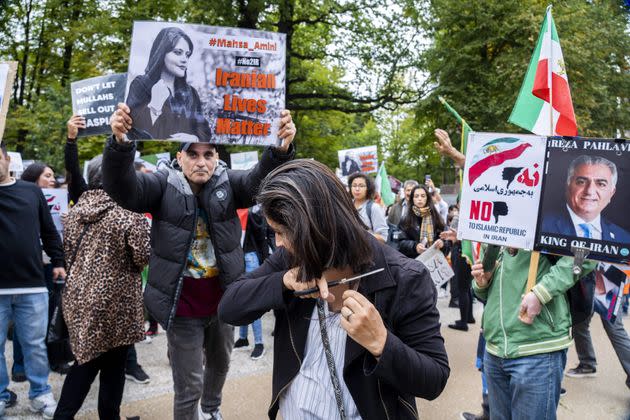 A protester cuts her hair during a rally against Iranian regime outside the House of Representatives in The Hague on Sept. 23, following the death of an Iranian woman after her arrest by the country's morality police in Tehran. (Photo: LEX VAN LIESHOUT/ANP/AFP via Getty Images)