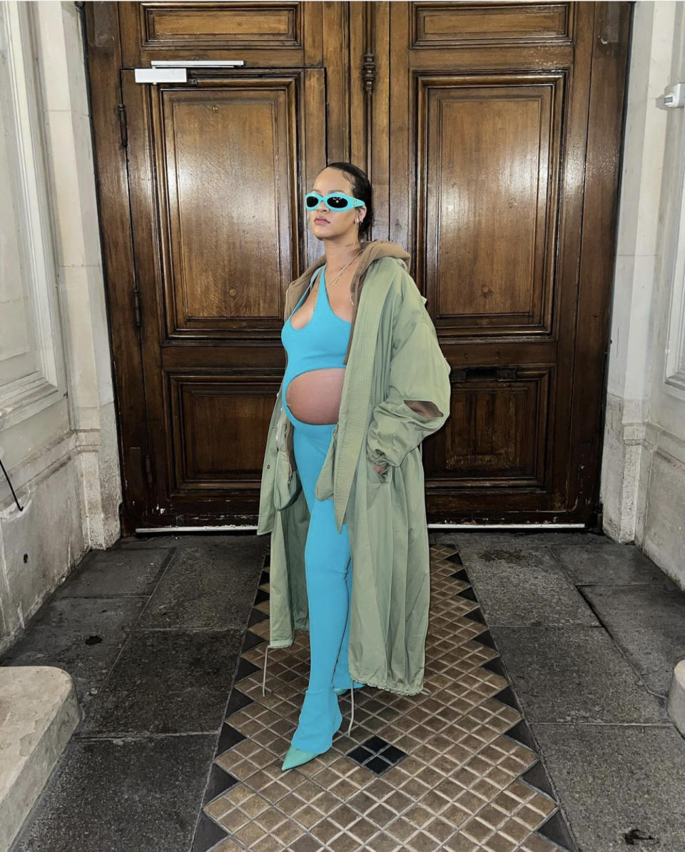 Rihanna poses in her outfit in front of doors