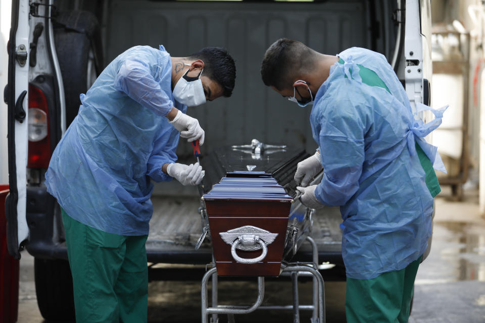 Trabajadores sanitarios sellan el ataúd de una víctima de COVID-19 en el Hospital Llavallol Dr. Norberto Raúl Piacentini en Lomas de Zamora, Argentina, el viernes 23 de abril de 2021. En Argentina se registran hasta ahora algo más de 3,1 millones de enfermos y más de 67.000 fallecidos. (AP Foto/Natacha Pisarenko)