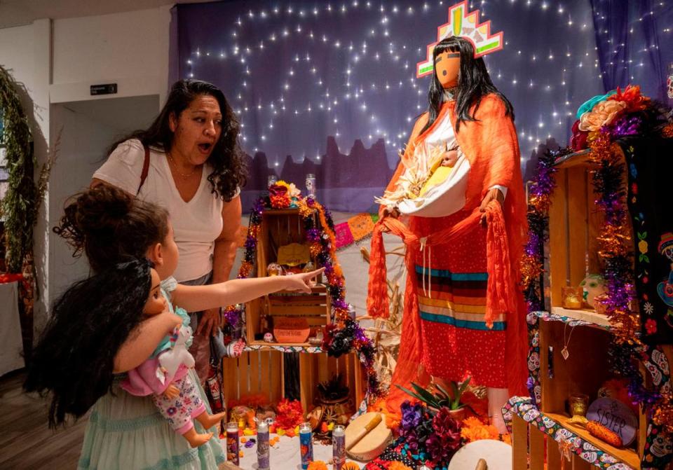 Luli Velasco and her daughter Maizie, 5, look over the ofrenda altar they worked to honor corn maiden and their ancetors at a reception at the Center Street Gallery on Thursday, Oct. 19, 2023, for Placerville’s Dia de los Muertos celebration.