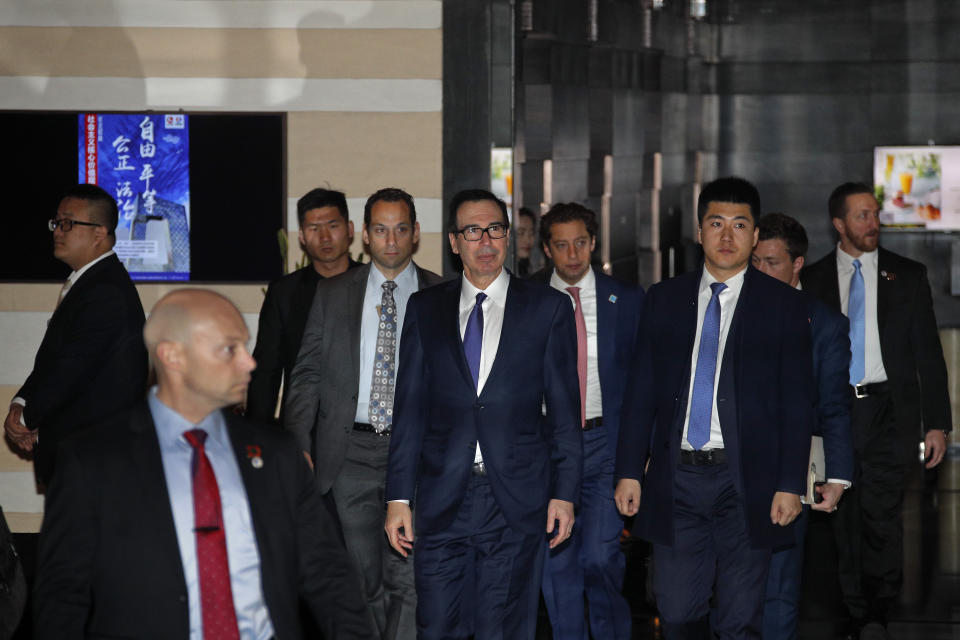 U.S. Treasury Secretary Steven Mnuchin, center, is escorted by delegations and security officers as he leaves a hotel to attend a new round of high-level trade talks with Chinese officials in Beijing, Thursday, Feb. 14, 2019. (AP Photo/Andy Wong)