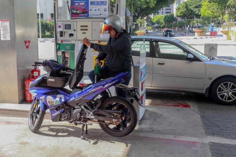 A man refuels his motorcycle at a petrol station in Kuala Lumpur as the movement control order kicks in on March 18, 2020. — Picture by Firdaus Latif