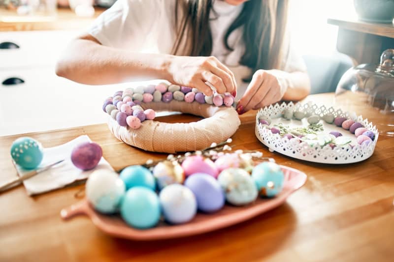 Close-up of women's hands making a wreath of eggs for Easter.