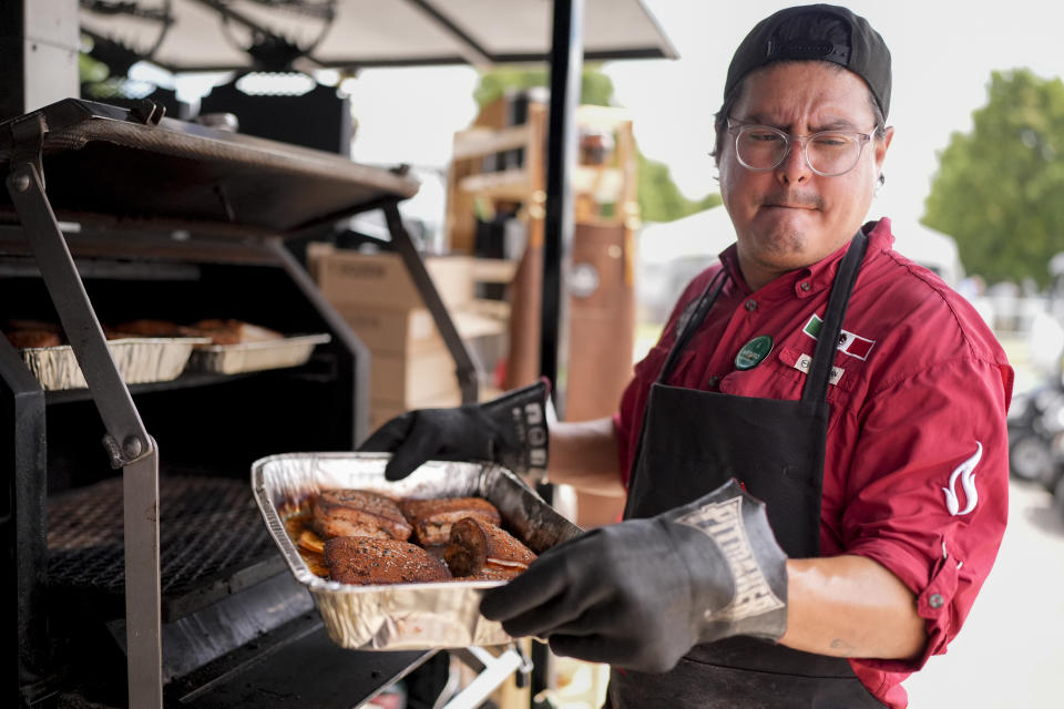 Arturo Gutierrez of the Sociedad Mexicano de Parrillieros team pulls meat from a grill at the World Championship Barbecue Cooking Contest, Friday, May 17, 2024, in Memphis, Tenn. (AP Photo/George Walker IV)
