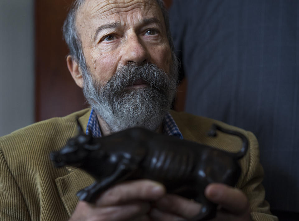 FILE - In this April 12 2017 file photo, Arturo Di Modica holds a model of his Charging Bull sculpture during a news conference in New York. Di Modica, the artist who sculpted the bronze bull statue in New York, an iconic symbol of Wall Street, has died in his native Sicily. Di Modica died at his home in Vittoria on Friday, Feb. 19, 2021 the town said in a statement. (AP Photo/Craig Ruttle, File)