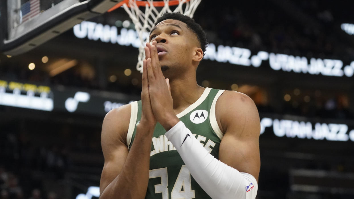 Giannis Antetokounmpo looks up with his hands placed together in a praying motion.