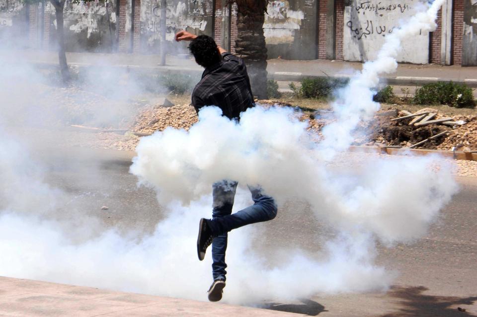 A bystander throws a tear gas canister that came back from the al-Azhar University campus after the canister was originally shot by the Egyptian security forces towards protesters at the school in Cairo, Egypt, Friday, May 2, 2014. Supporters of Egypt's Islamist President Mohammed Morsi continue to protest in the streets as retired Field Marshal Abdel-Fattah el-Sissi, who led last year's overthrow of Morsi, appears poised to win in the presidential election planned this month. (AP Photo/Mohammed Abu Zaid)