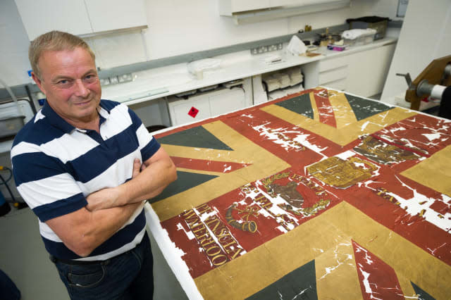 Gary Lawrence age 58 with his Waterloo flag. See National copy NNFLAG: A military antiques collector has discovered one of the last remaining flags from the Battle of Waterloo in a shoe box. Gary Lawrence bought the collection of items through an online auction and found fragments of the flag, which dates back 200 years. He is now restoring the flag, which belonged to the Coldstream Guards 15th Light Company, with a team from the V&A museum. The 58-year-old runs Waterloo Militaria with his son Luke, and says he has never found anything this historically significant.