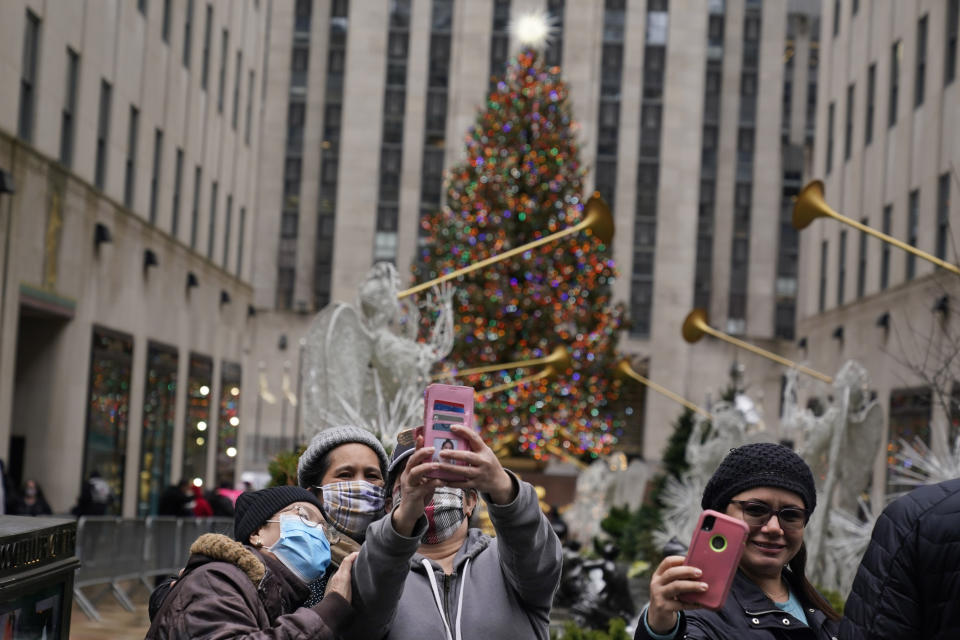 People take pictures of themselves with the Rockefeller Center Christmas tree in New York on Christmas day, Friday, Dec. 25, 2020. The coronavirus upended Christmas traditions, but determination and imagination kept the day special for many. (AP Photo/Seth Wenig)