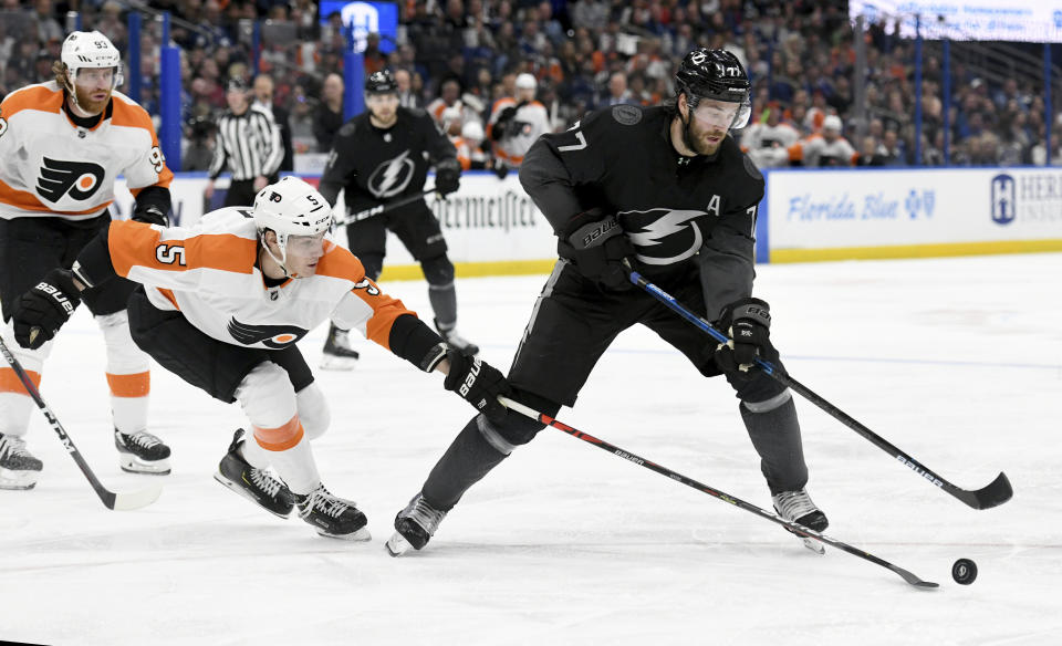 Philadelphia Flyers defenseman Philippe Myers (5) and Tampa Bay Lightning defenseman Victor Hedman (77) battle for the puck during the second period of an NHL hockey game Saturday, Feb. 15, 2020, in Tampa, Fla. (AP Photo/Jason Behnken)