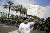 <p>A man walks with a sign as Orange County Sheriff’s deputies advance in riot gear to disperse protesters near the Anaheim Convention Center on May 25, 2016, in Anaheim, Calif., after Republican presidential candidate Donald Trump held a rally. (AP Photo/Jae C. Hong) </p>