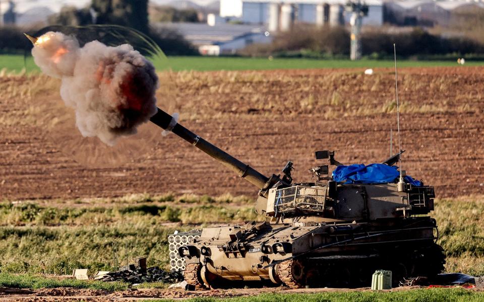 A shockwave erupts as a projectile exits the barrel of an Israeli army self-propelled artillery Howitzer firing rounds from southern Israel toward the Gaza Strip