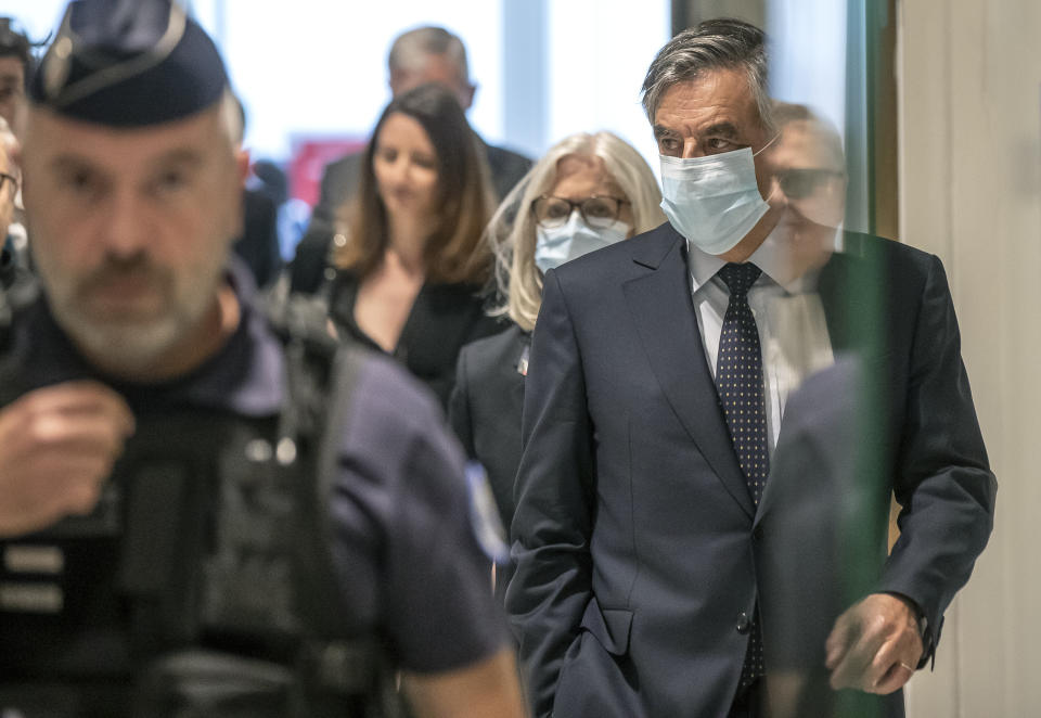 France's former Prime Minister Francois Fillon, right, and his wife Penelope wear protective masks as they arrive at Paris courthouse, in Paris, Monday, June 29, 2020. A Paris court is set to render or postpone a verdict in the fraud trial of former Prime Minister Francois Fillon on Monday. (AP Photo/Michel Euler)