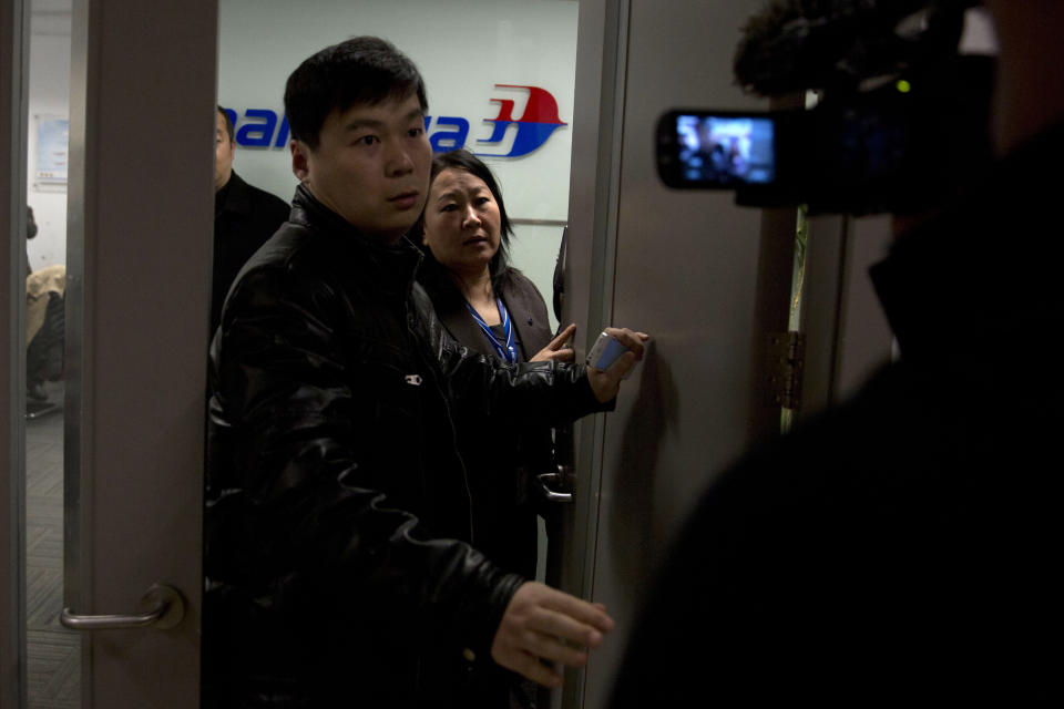 Staff members of Malaysian Airlines' office try to chase out journalists gathering outside the office in Beijing's International Airport, China, Saturday, March 8, 2014. A Malaysia Airlines Boeing 777-200 carrying 239 people lost contact over the South China Sea early Saturday morning on a flight from Kuala Lumpur to Beijing, and international aviation authorities still hadn't located the jetliner several hours later. (AP Photo/Ng Han Guan)