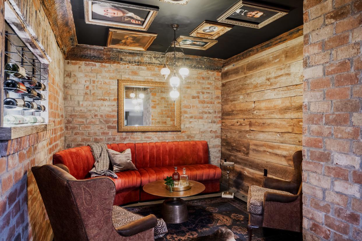 The speakeasy-style bourbon and wine cellar at Mallard Hall in Fisherville, Kentucky features an art collection on the ceiling, a full bar with premium GE appliances, a theater area, and a repurposed Leda & The Swan custom-etched illuminated window feature.