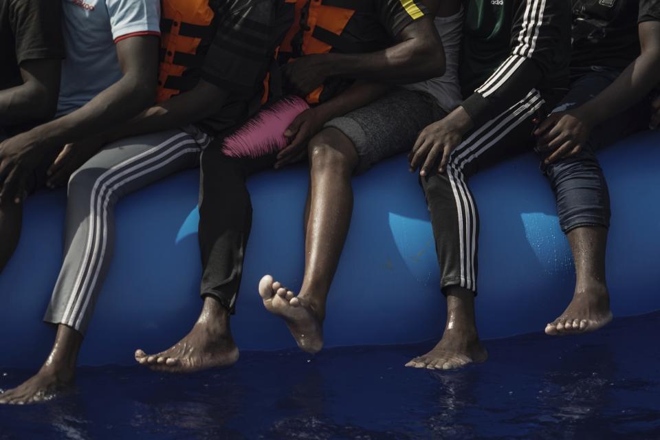 In this Sept. 17, 2019 photo, migrants sit on an overcrowded rubber boat as they wait to be rescued by the Ocean Viking humanitarian ship run by SOS Mediterranée and Doctors Without Borders in the Mediterranean Sea north of Libya. The EU has sent more than 327.9 million euros to Libya, with an additional 41 million approved in early December, largely funneled through UN agencies. However, the AP found that in a country without a functioning government, huge sums of European money have been diverted - in some cases with the knowledge of UN officials - to intertwined networks of militiamen, traffickers and coast guard members who exploit migrants. (AP Photo/Renata Brito)