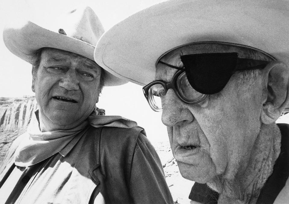 (Original Caption) 1971-Hollywood, CA-: Director John Ford is a giant whose shadow stretches back a half-century in motion picture history and who may yet pioneer with camera and film in the year to come. He is shown in discussion here with actor John Wayne. Filed 11/19/1971.