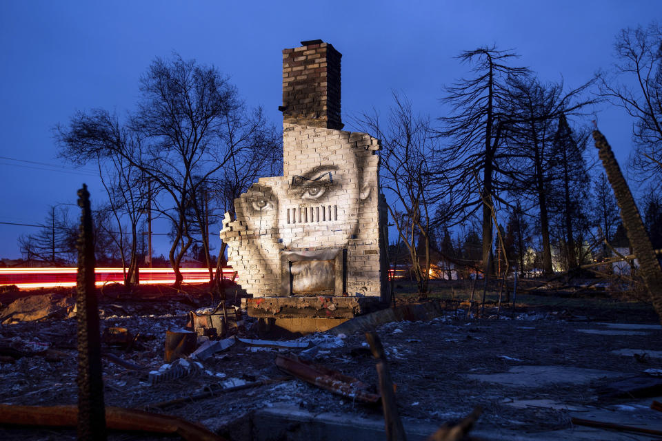 In this Feb. 8, 2019, photo, a mural by artist Shane Grammer adorns the chimney of a residence leveled by the Camp Fire in Paradise, Calif. Grammer says he painted murals throughout the fire-ravaged town to convey hope in the midst of destruction. In the 100 days since the wildfire nearly burned the town of Paradise off the map, the long recovery is just starting. (AP Photo/Noah Berger)