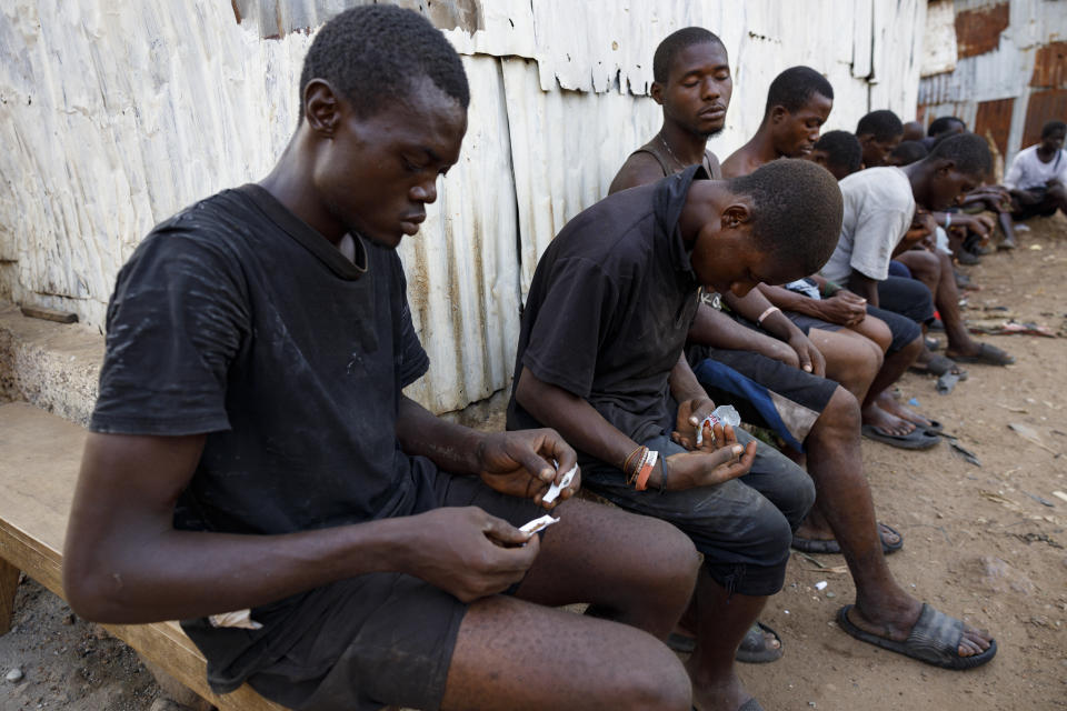 A young man rolls Kush as other users sleep at a hideout in Freetown, Sierra Leone, Monday, April 29, 2024. Sierra Leone declared a war on the cheap synthetic drug, calling it an epidemic and a national threat. The drug is ravaging youth, and healthcare services are severely limited. (AP Photo/ Misper Apawu)