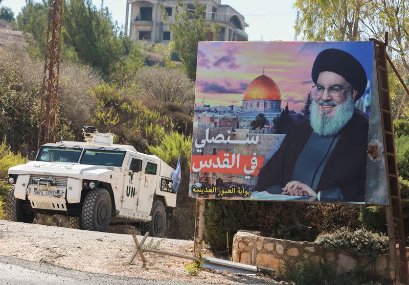 A UN peacekeepers (UNIFIL) vehicle drives near a picture showing Lebanon's Hezbollah leader Sayyed Hassan Nasrallah in Adaisseh village