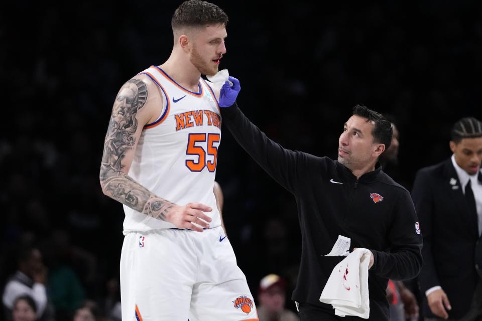 A trainer helps New York Knicks' Isaiah Hartenstein (55) after he was hurt during the first half of an NBA basketball game against the Brooklyn Nets Wednesday, Dec. 20, 2023, in New York. (AP Photo/Frank Franklin II)