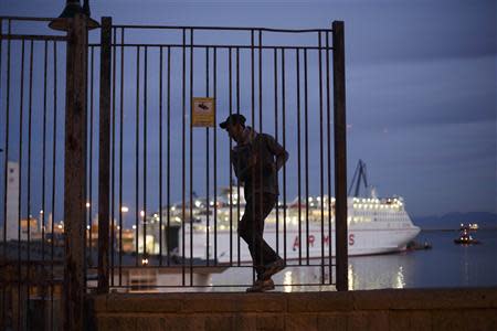 A Moroccan youth climbs along a wall overlooking Melilla harbour in Spain's north African enclave as a ship prepares to leave towards mainland Spain November 30, 2013. REUTERS/Juan Medina