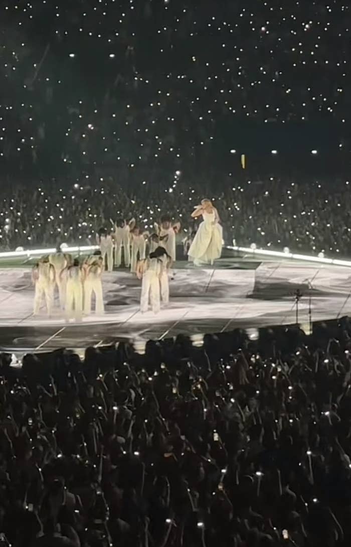 Taylor floats above the stage, singing, as dancers gather around