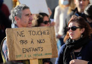 A man holds a placard reads "Don't touch our children" as he demonstrates in Bayonne, southwestern France, against wearing masks at school, Sunday, Nov. 29, 2020. In France, wearing a mask at school is compulsory from 6 years old. (AP Photo/Bob Edme)