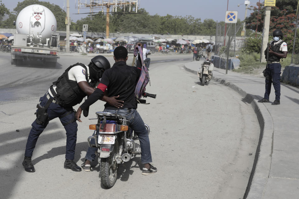 A police officer pats down a motorcyclist at a checkpoint in Port-au-Prince, Haiti, Saturday, July 1, 2023. (AP Photo/Odelyn Joseph)