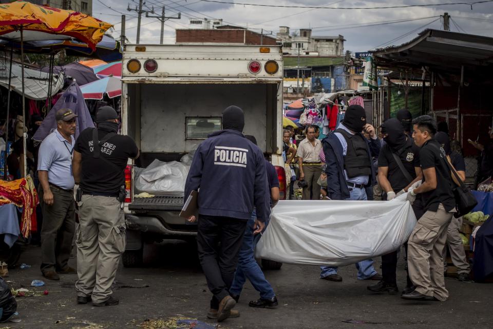 Police investigators carry a body to a forensic vehicle, after a shootout between private security guards and gang members, at the central market in San Salvador, El Salvador, Wednesday, March 15, 2017. At least 30 people, mostly gang members, died in the last 24 hours in El Salvador on one of the most violent days so far this year. (AP Photo/Salvador Melendez)