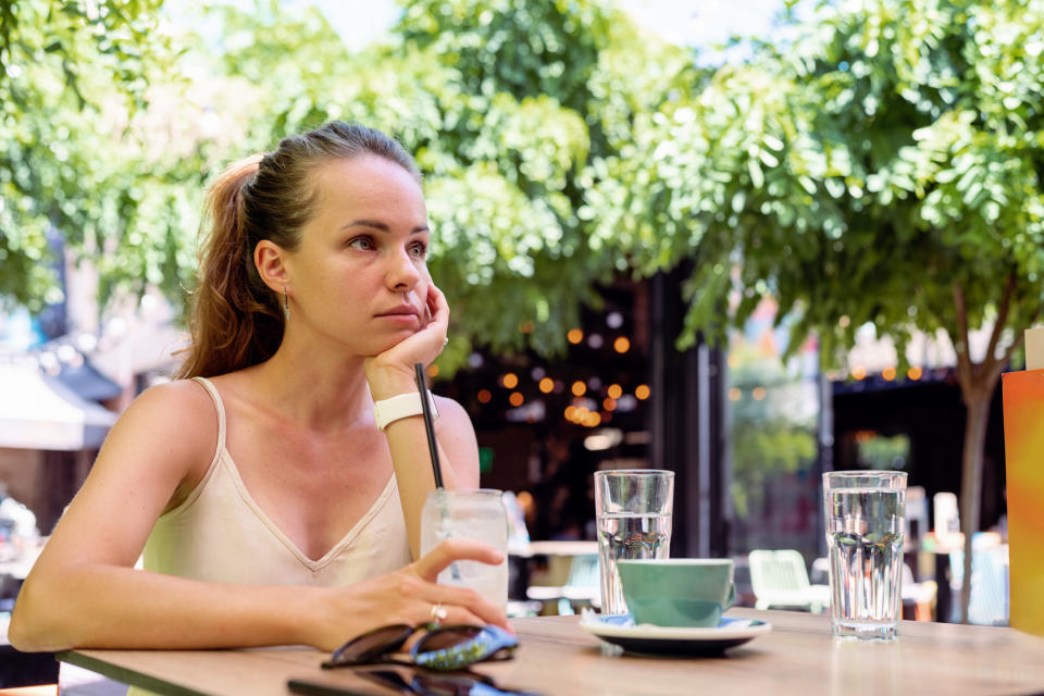 Woman sitting at a cafe table looking bummed out