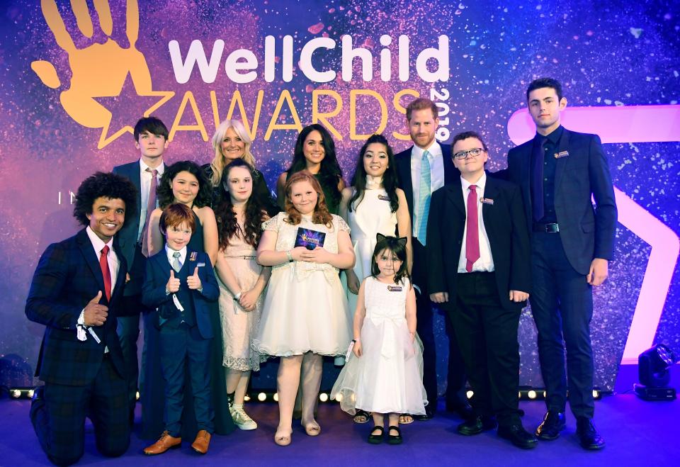 A photo of Britain's Prince Harry, Duke of Sussex (3R), and Britain's Meghan, Duchess of Sussex (back row C) pose for a group photograph with award winners and presenters during the annual WellChild Awards in London on October 15, 2019.