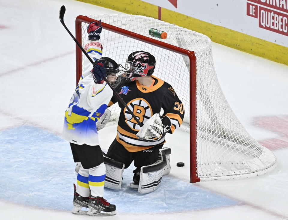 Ukraine peewee team's Ivan Bilozerov, left, celebrates his team's winning goal against Boston Junior Bruins goalie James Boccuzzi during a hockey game, Saturday, Feb, 11, 2023, in Quebec City. (Jacques Boissinot/The Canadian Press via AP)