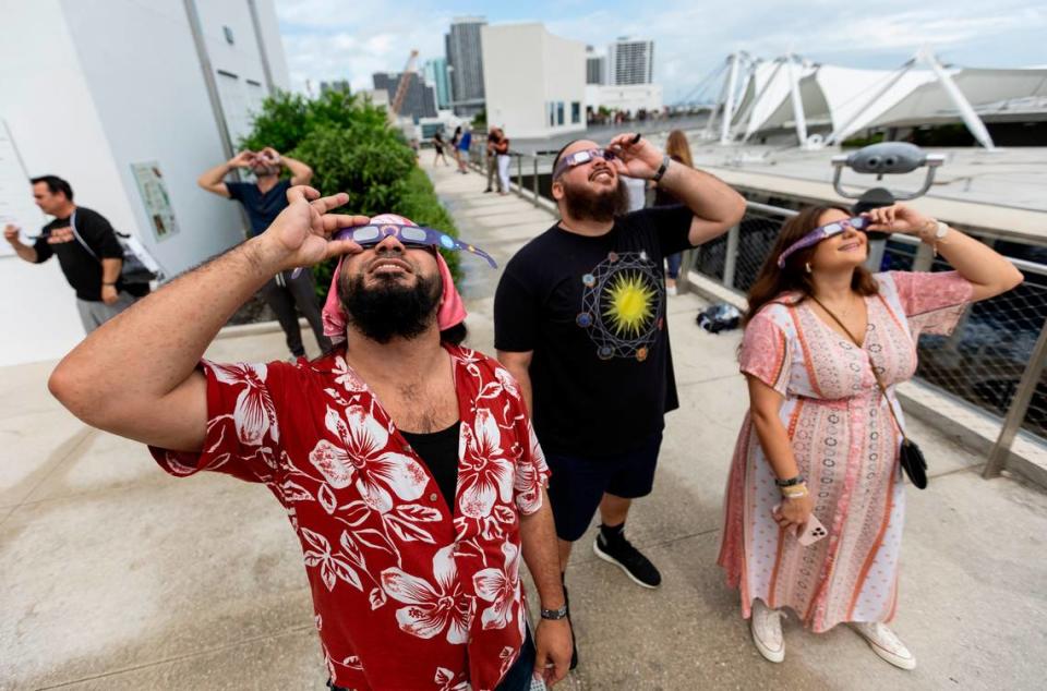 De izquierda a derecha: Albert Rivera, de 36 años; Alex Quevedo, de 35, y Shannen Mirarchi, de 31, observan un eclipse solar parcial en el Frost Science Museum, el sábado 14 de octubre de 2023, en el downtown de Miami, Florida.