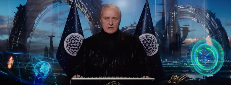 A man in futuristic garb gives a speech