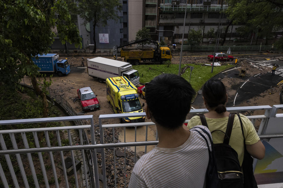 A pedestrian takes photographs of a flooded road following heavy rainstorms in Hong Kong, Friday, Sept. 8, 2023. (AP Photo/Louise Delmotte)